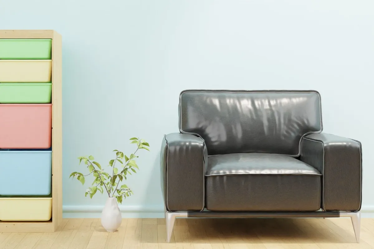 A stylish living room with a leather sofa, colorful storage options, and a vase of greenery, showcasing organized space.