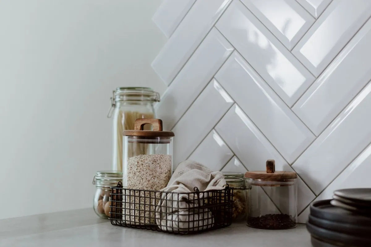 A clean kitchen counter with glass jars filled with pasta and grains, showcasing effective decluttering.