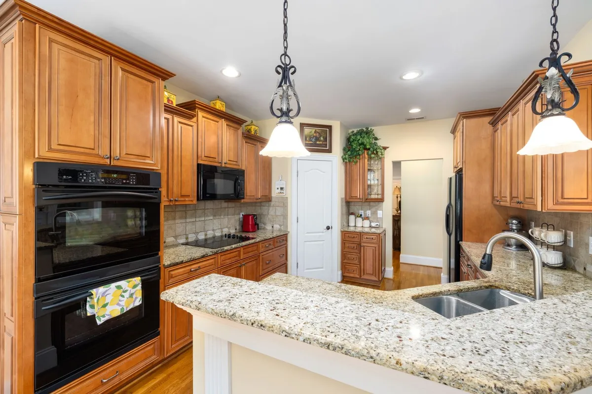 A spacious kitchen with wooden cabinets and granite countertops, illustrating effective clutter organization.
