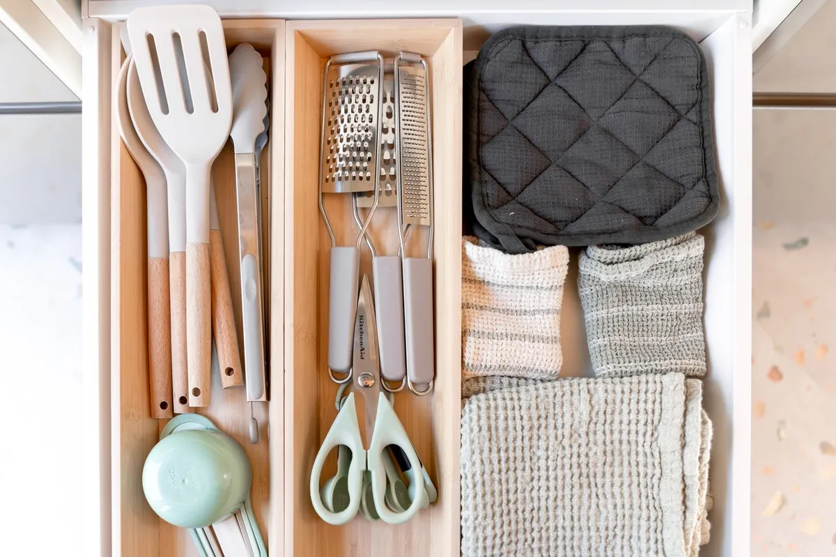 Neatly arranged kitchen tools and textiles in a drawer highlight the benefits of effective organization.