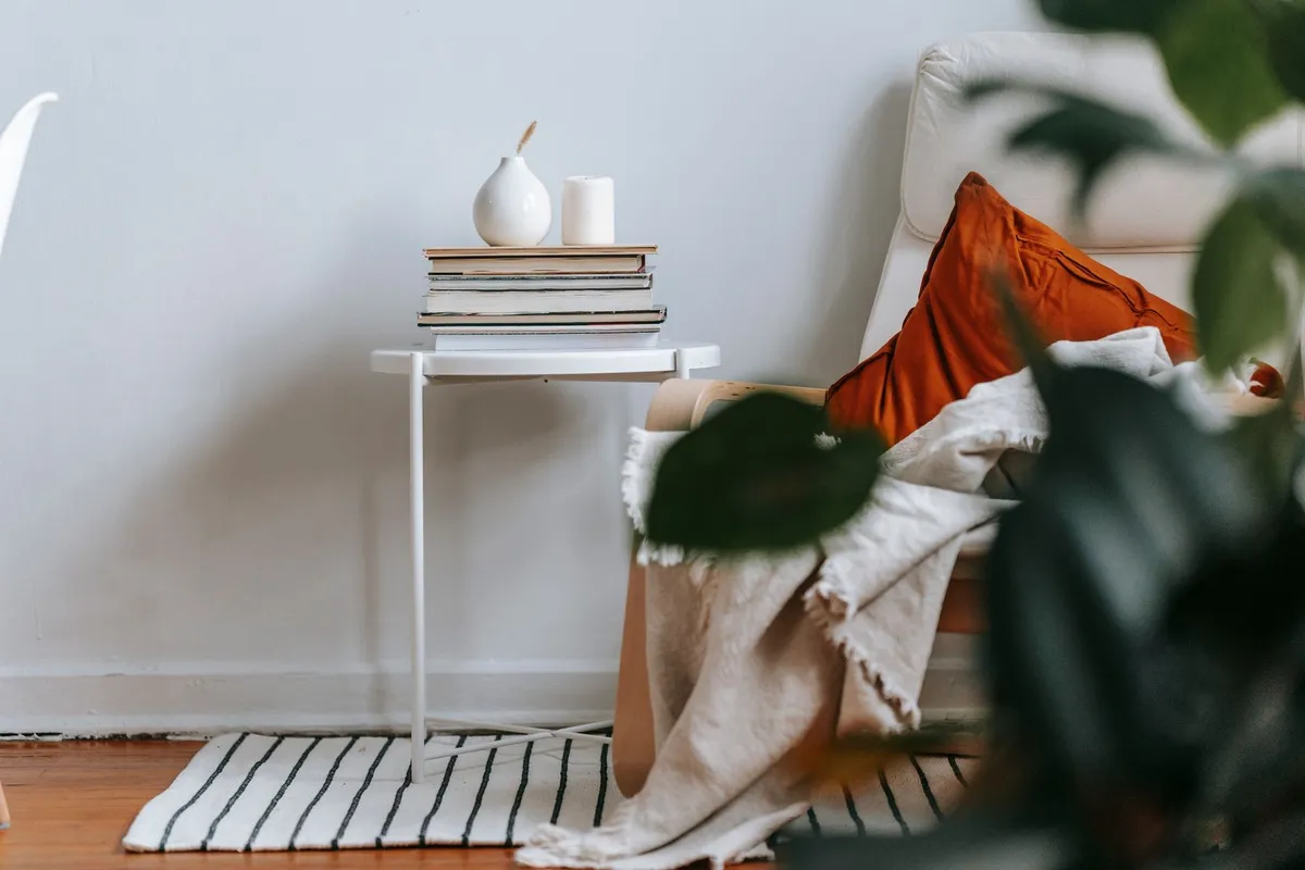 A cozy light room with an armchair, small table, books, and a vase, highlighting the importance of organization.